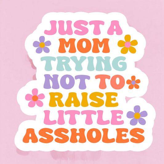 Colorful sticker with the text 'JUST A MOM TRYING NOT TO RAISE LITTLE ASUSLIES' arranged in a playful layout with floral accents.