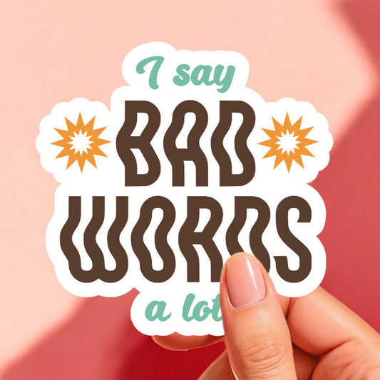 a white sticker that reads i say bad words a lot in brown and teal with a mustard yellow sun on either side of the word bad