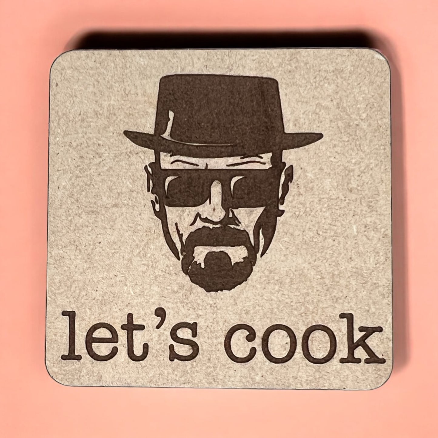 A square magnet with a humorous quote printed on it, placed against a pink background.