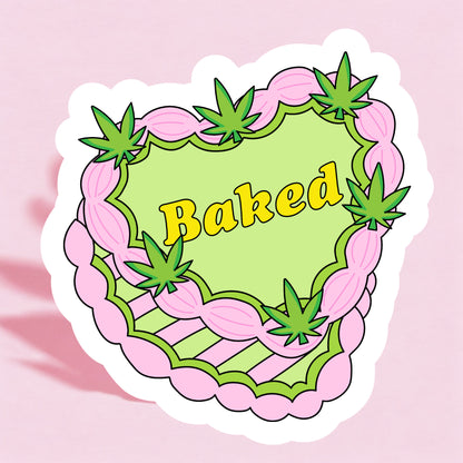 A colorful sticker with a pink and green cake design and the word 'Baked' written in the center, decorated with cannabis leaf motifs.