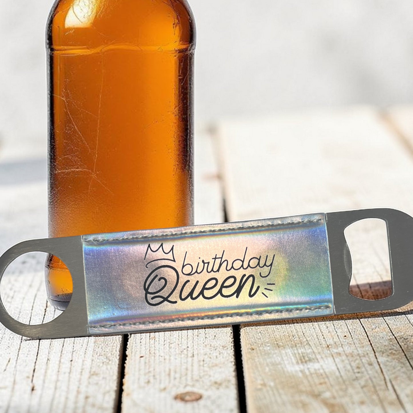 Bottle opener with 'Birthday Queen' text next to a bottle on a wooden surface