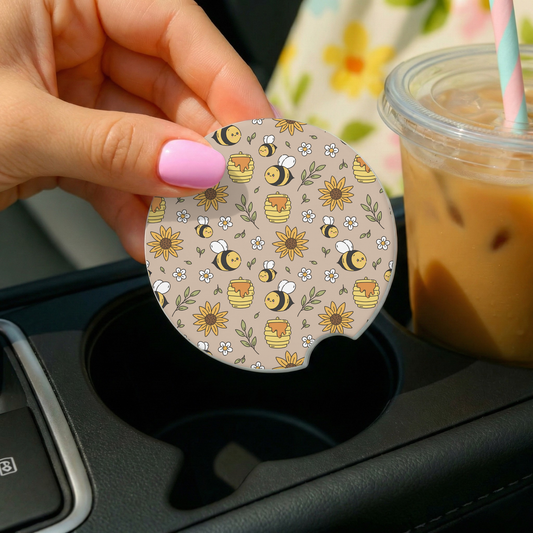 a hand holding a car coaster with a bee theme