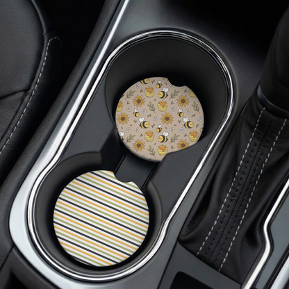 Two car coasters with floral and striped designs in a cup holder.
