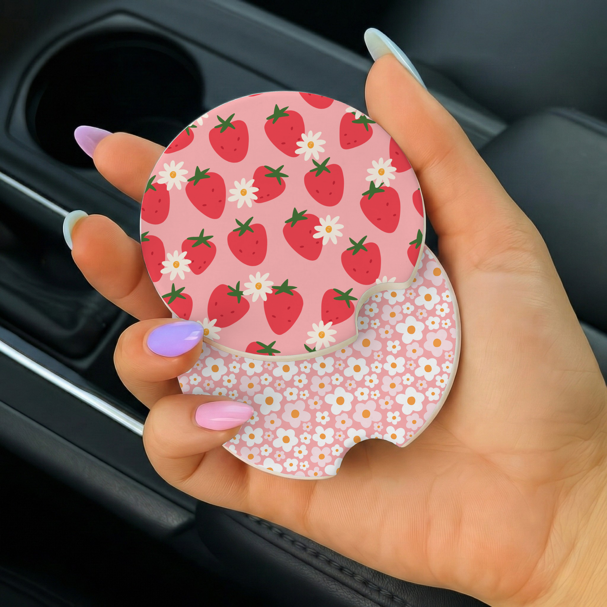 Hand holding a pink car coaster with strawberry pattern