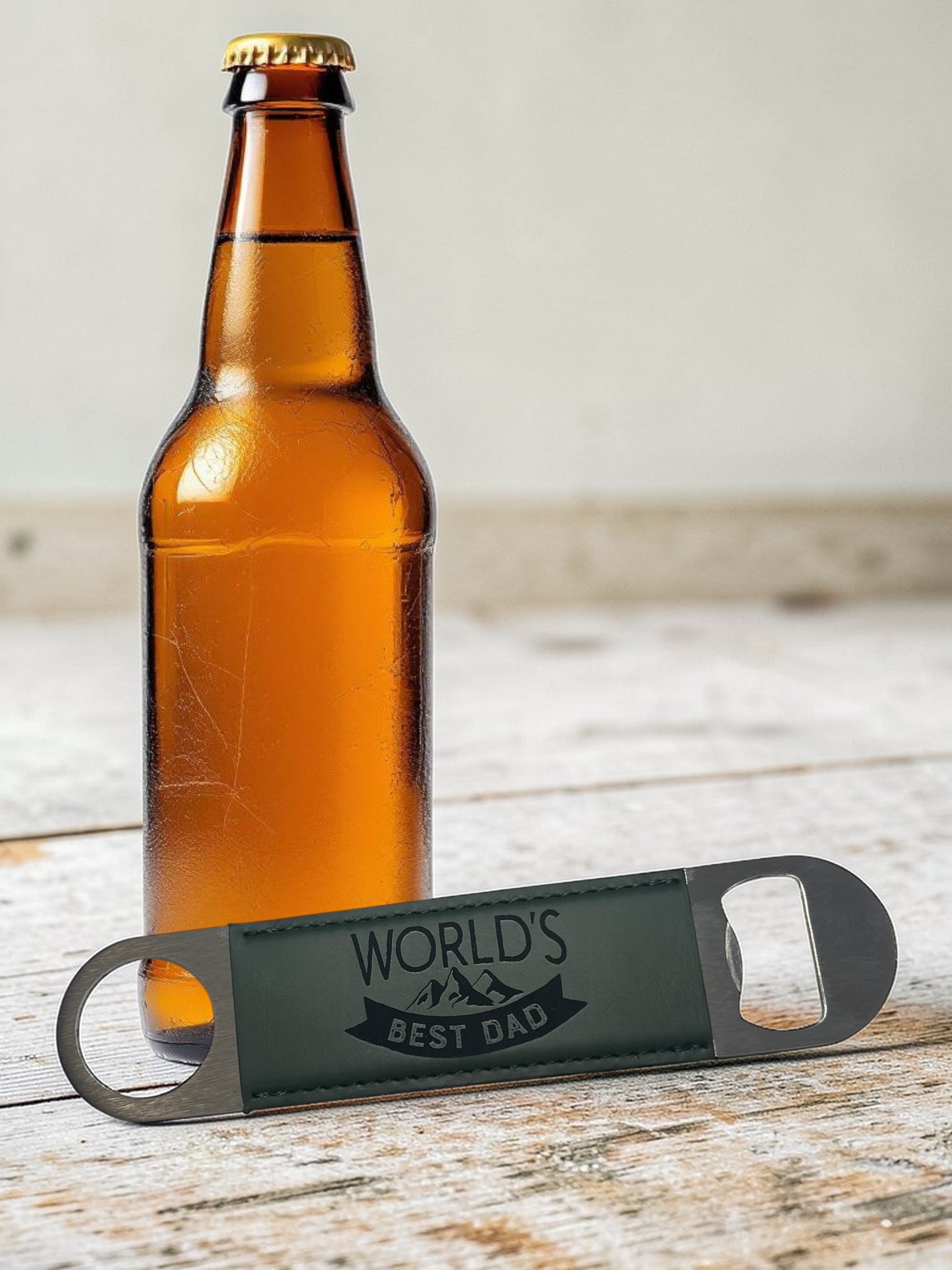 Brown beer bottle with a 'World's Best Dad' bottle opener on a wooden surface