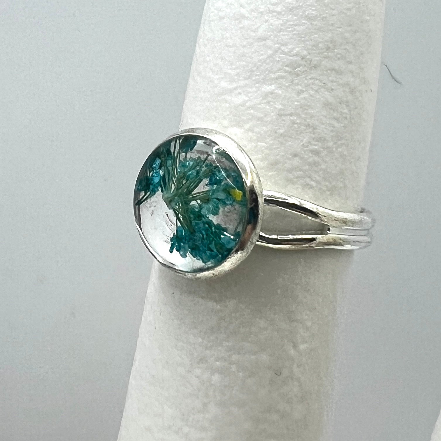 Silver ring with a round blue queen anne's lace flower on a white background