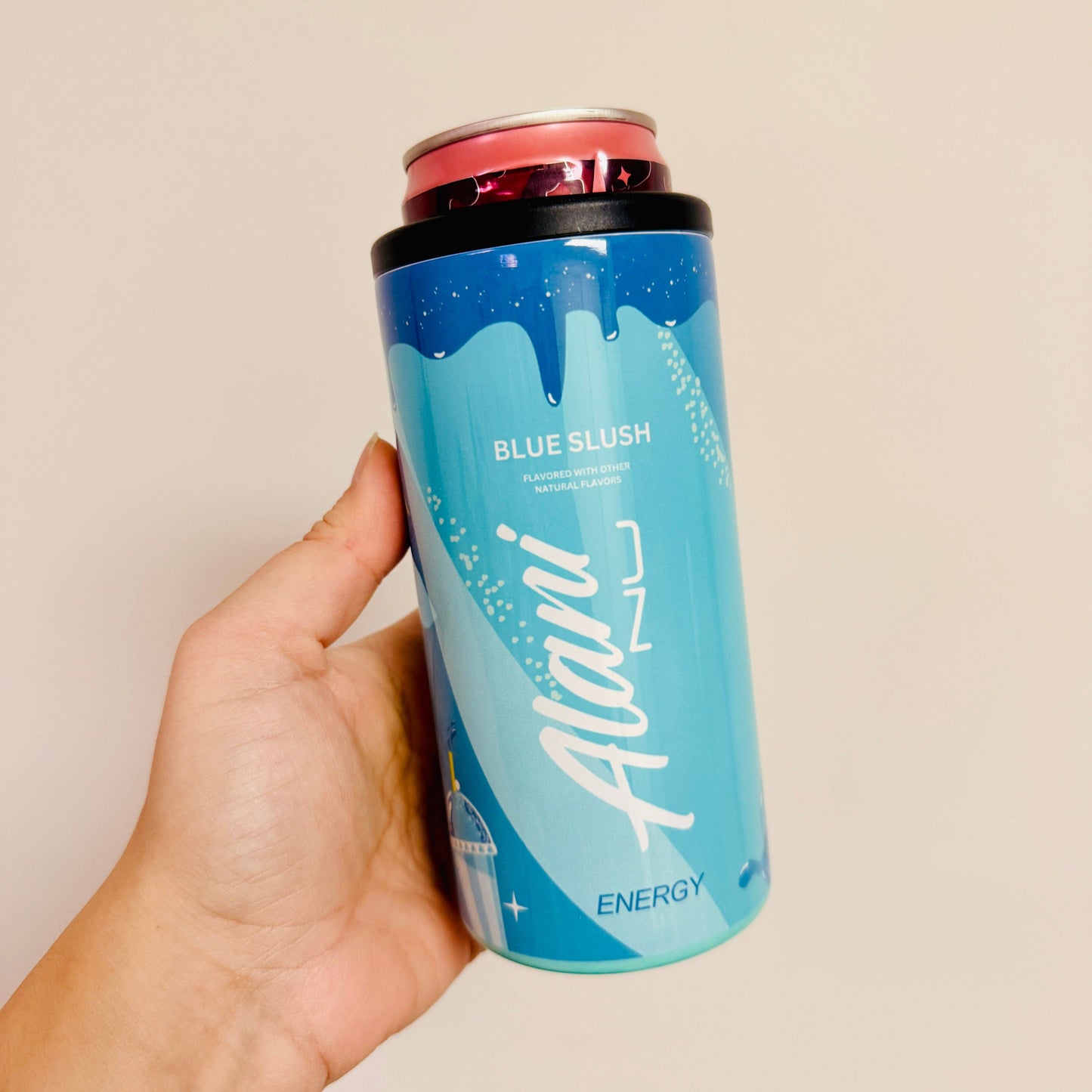 Hand holding a blue energy drink can with 'Alani' branding against a beige background