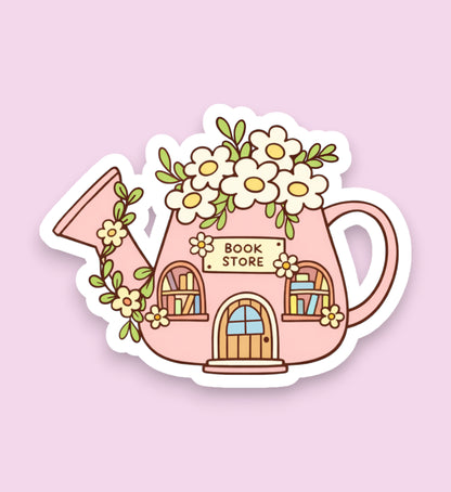 Sticker of a pink watering can shaped like a book store with flowers on a light pink background