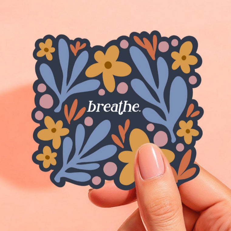 a sticker with a navy blue background and colorful flowers that reads breathe