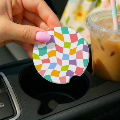 Colorful checkered car coaster held over a cup holder with a drink in the background