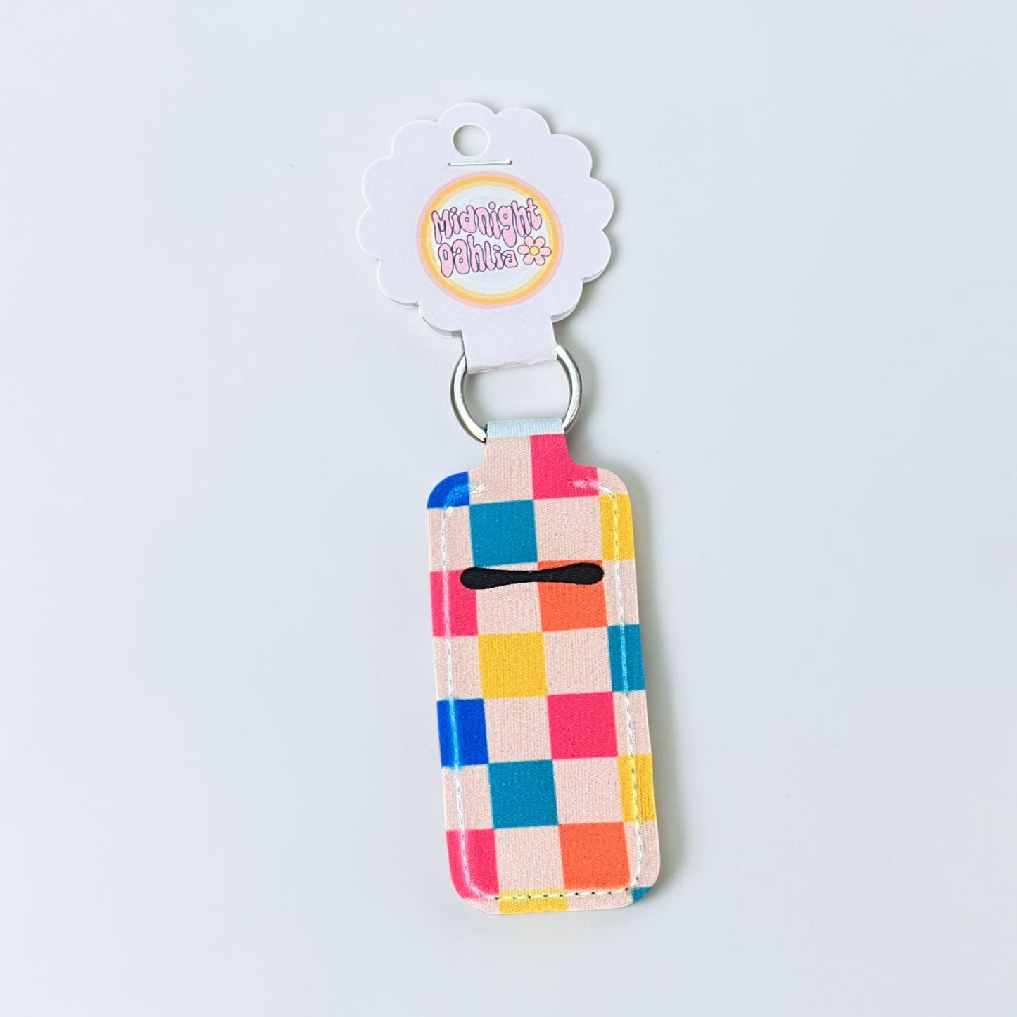 Colorful checkered keychain with a branded tag on a light gray background