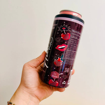 Hand holding a can of Alani Nu energy drink with a cherry flavor on a plain background