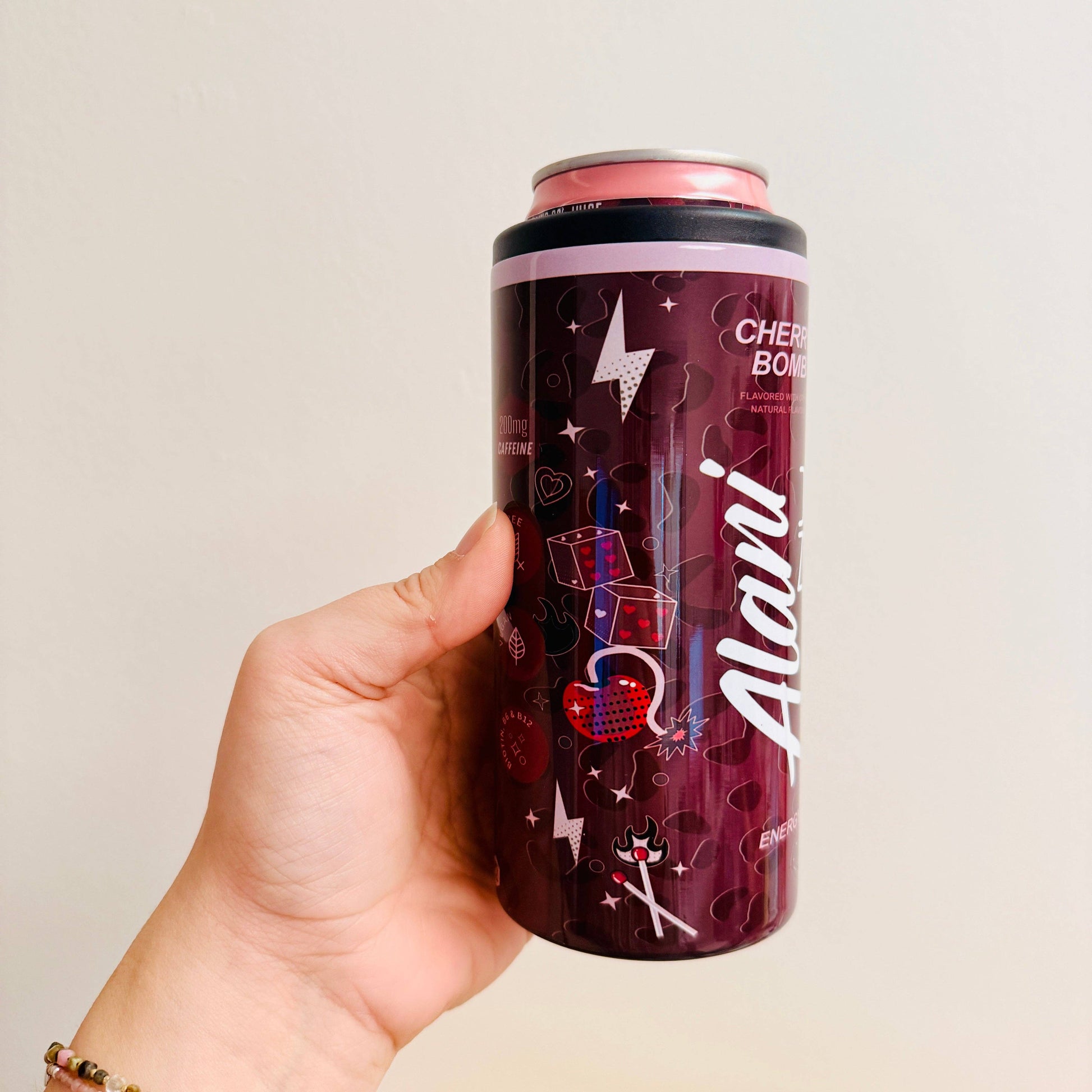Hand holding a cherry bomb flavored can against a plain background