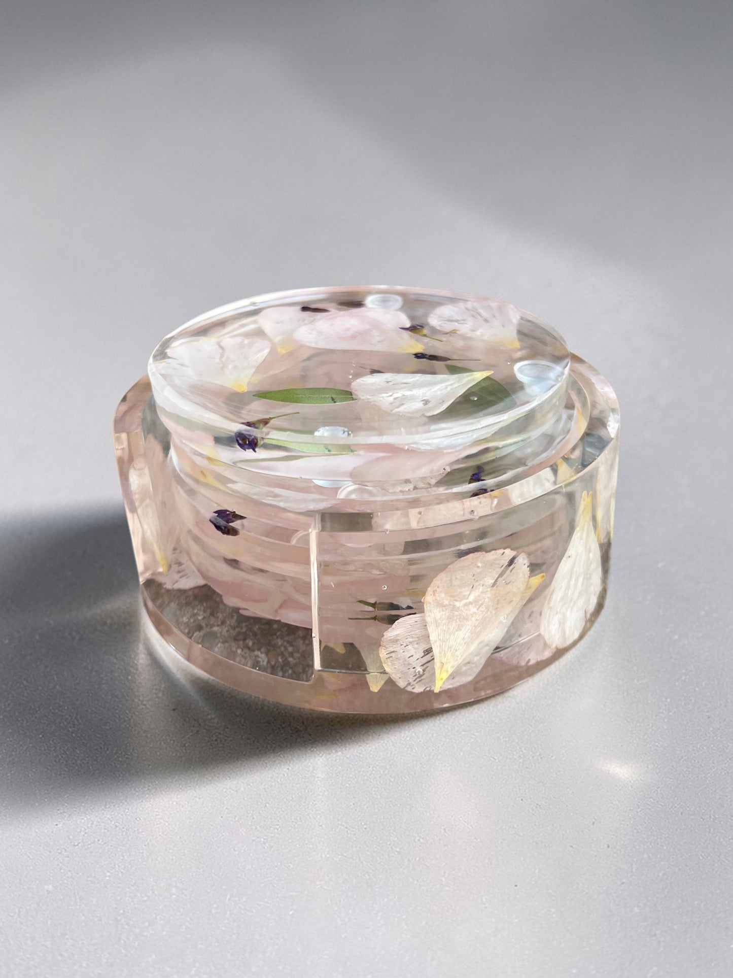 clear resin coaster set with floral elements on a gray background
