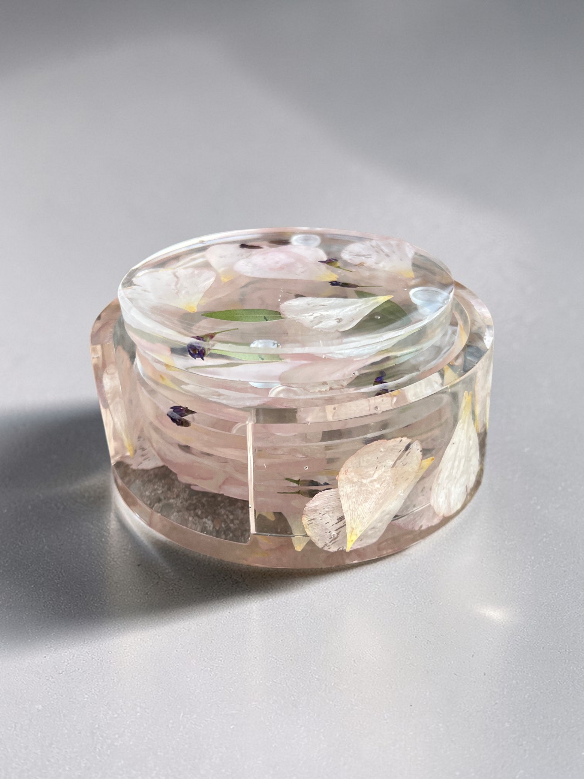 clear resin coaster set with floral elements on a gray background