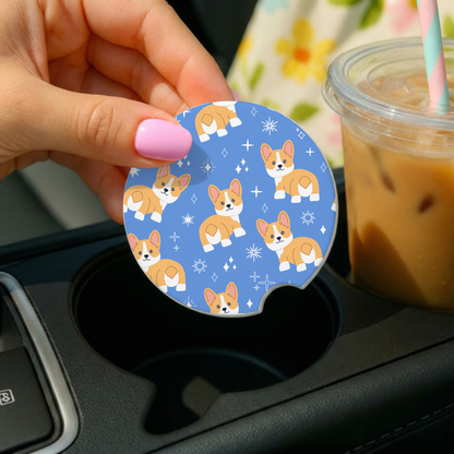 Hand holding a car coaster with corgi pattern over a cup holder with iced coffee.