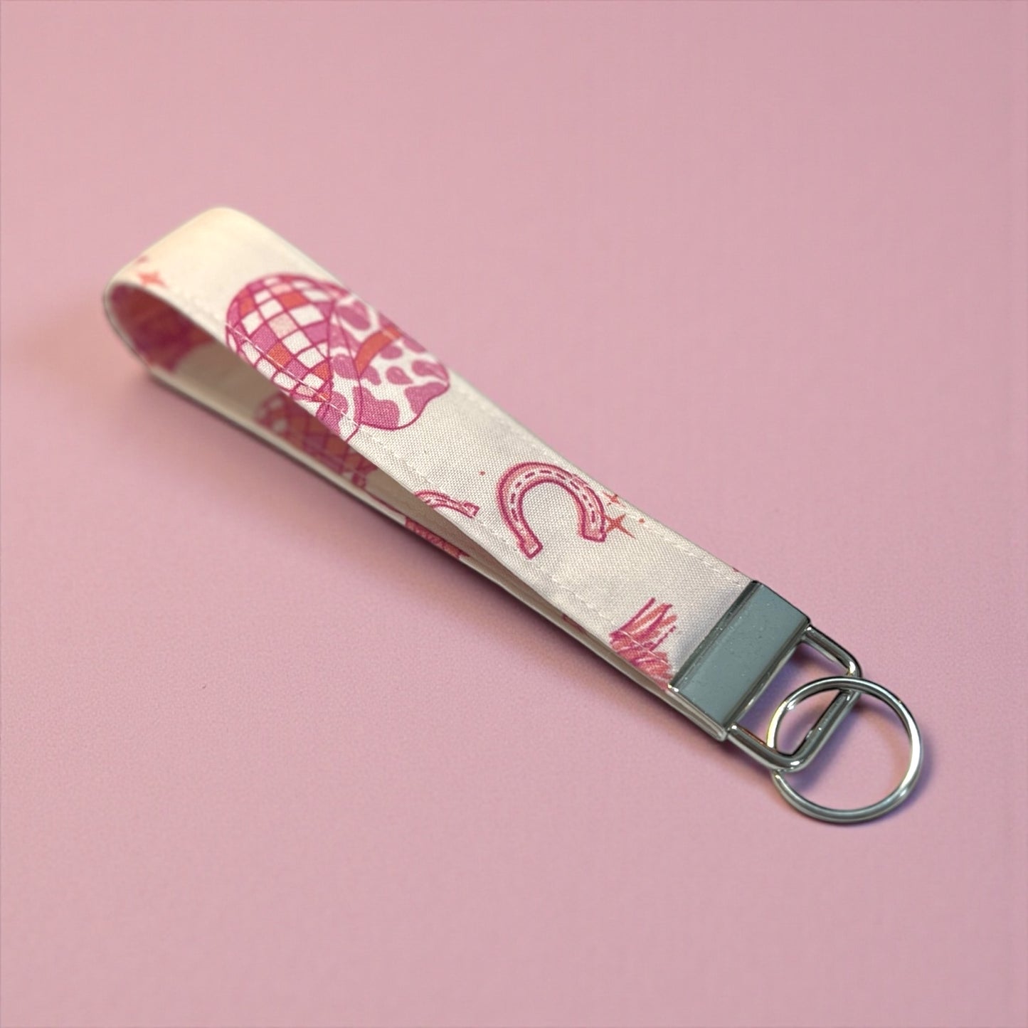 Keychain with pink patterns on a beige strap against a pink background
