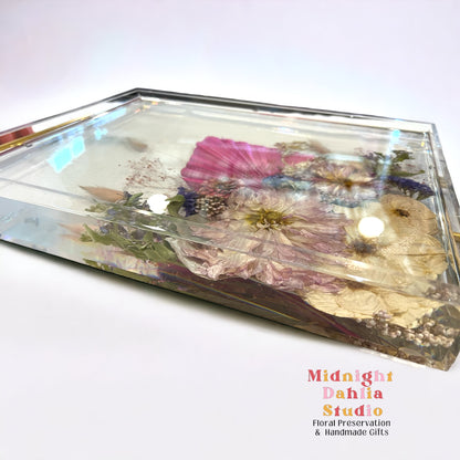 A custom acrylic tray filled with bright flowers including a peony and roses and crystal clear resin.  A beautiful way to preserve a bridal bouquet.