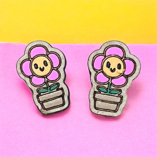 Flower-shaped earrings with smiling faces on a pink and yellow background