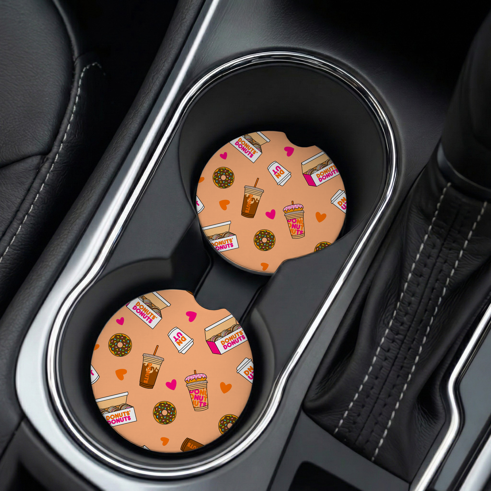 Two car coasters with a donut and coffee pattern in a car cup holder.