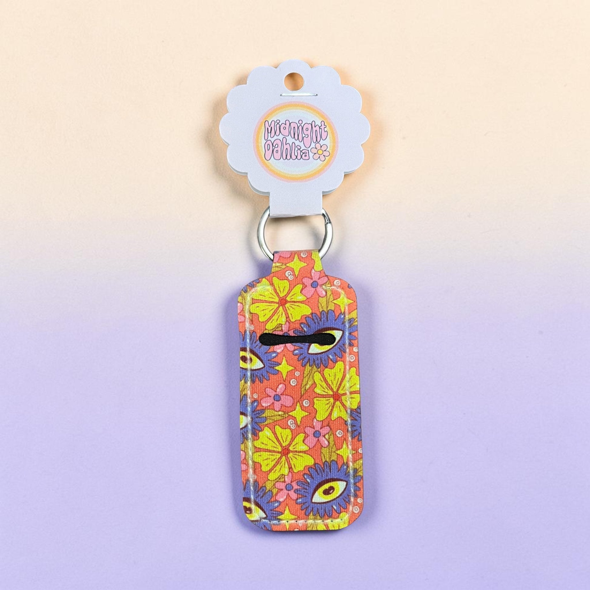 Colorful floral keychain with a tag on a light purple background