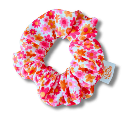Floral patterned scrunchie with a visible brand tag on a white background