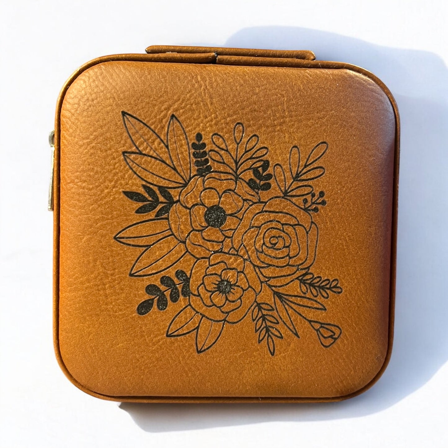 a brown rawhide jewelry box engraved with a black floral pattern