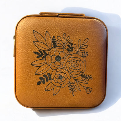 a brown rawhide jewelry box engraved with a black floral pattern