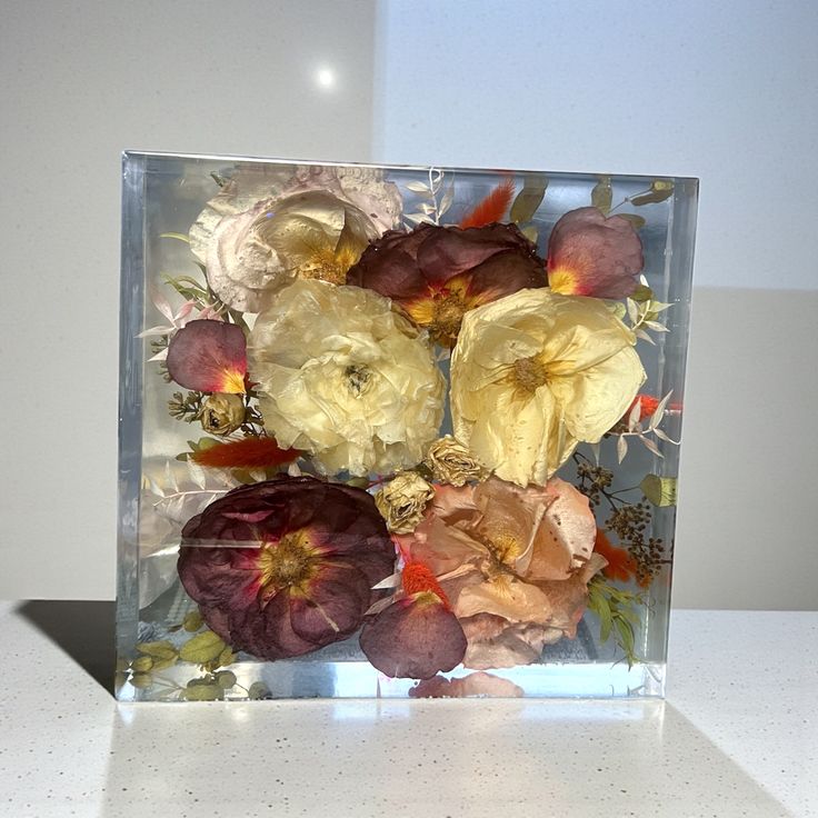 Pressed flowers in a clear resin block on a white surface