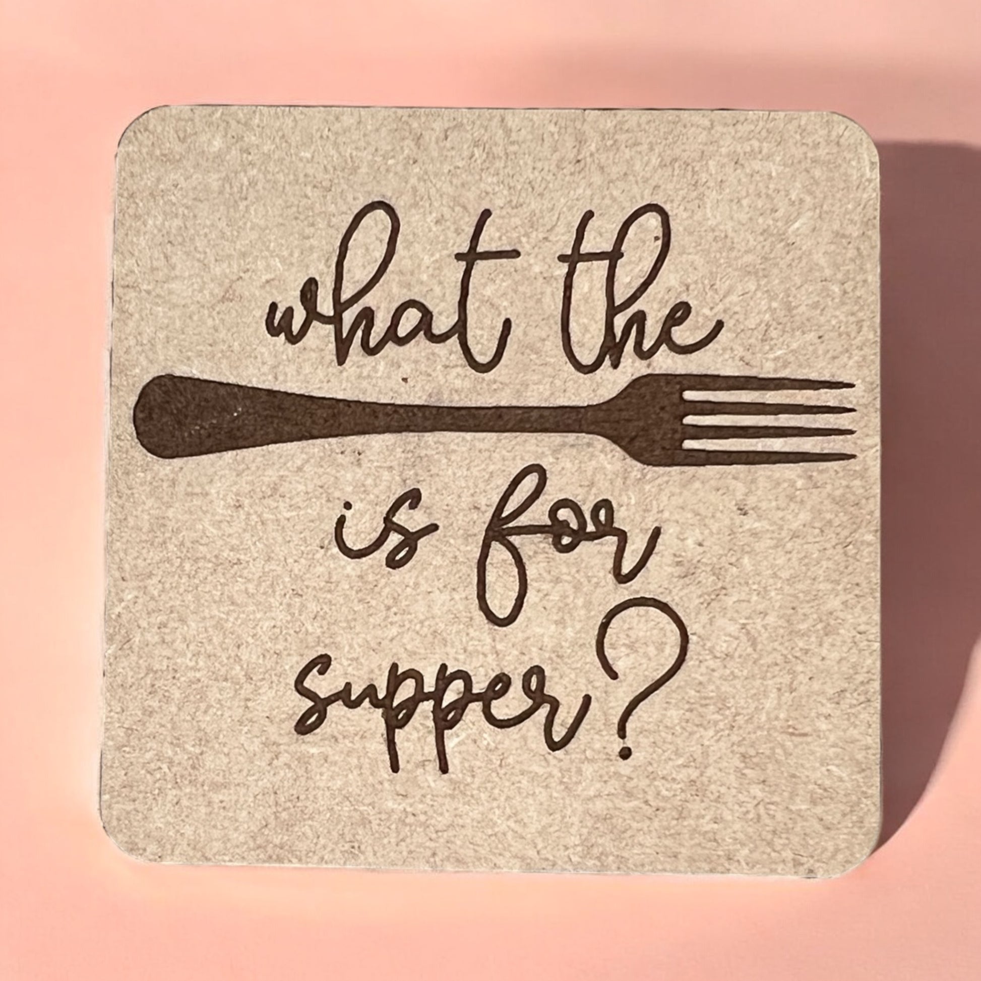 A square magnet with a humorous quote printed on it, placed against a pink background.