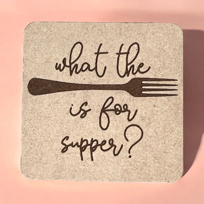 A square magnet with a humorous quote printed on it, placed against a pink background.