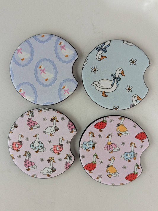 Four round ceramic coasters with duck designs on a white background