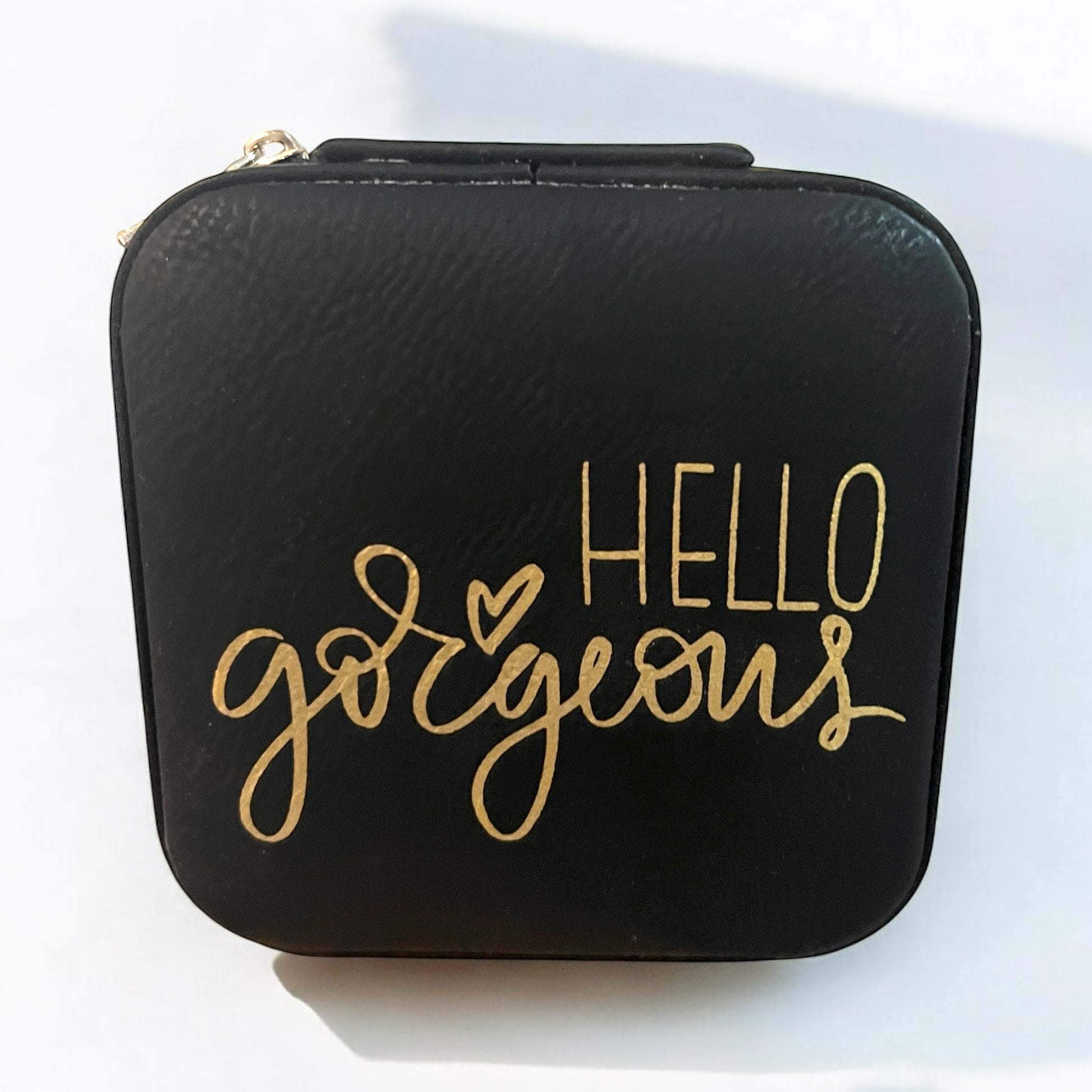 a black jewelry box engraved in gold with the words "hello gorgeous"