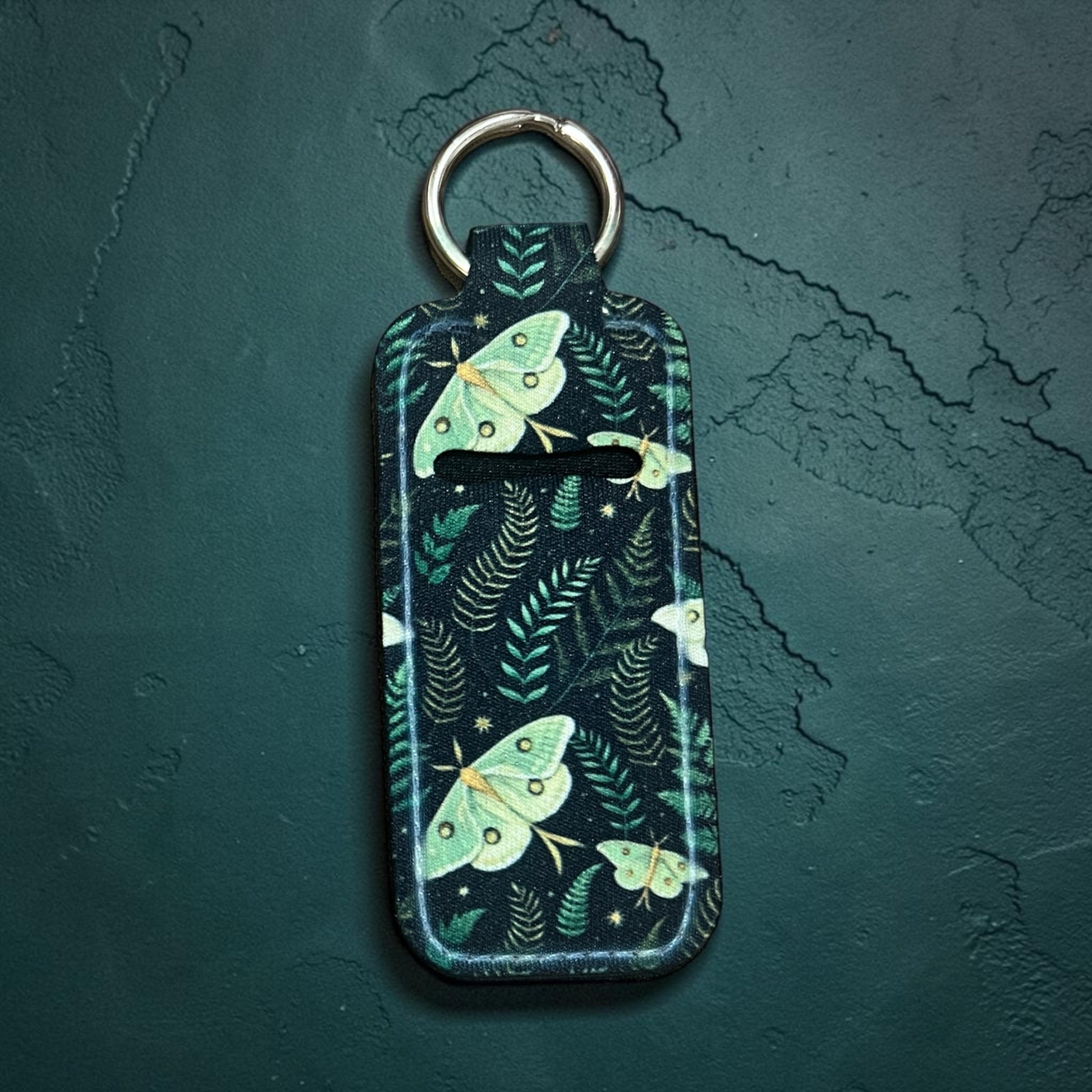 Keychain with moth design on a dark green background