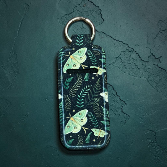 Keychain with moth design on a dark green background