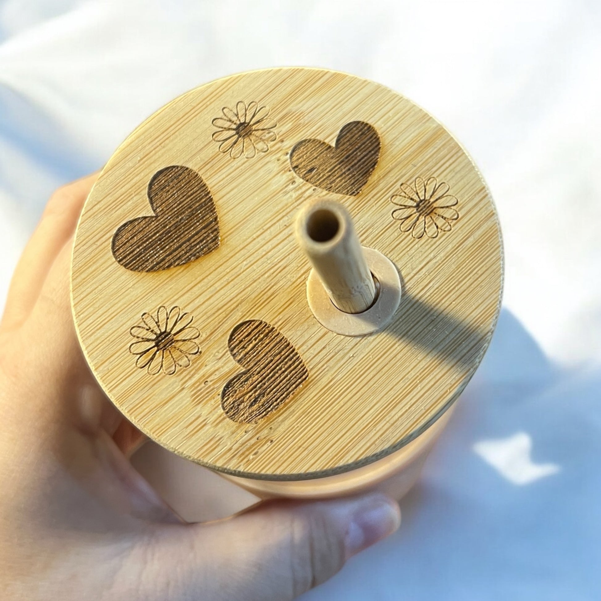 a bamboo tumbler lid engraved with hearts and daisies