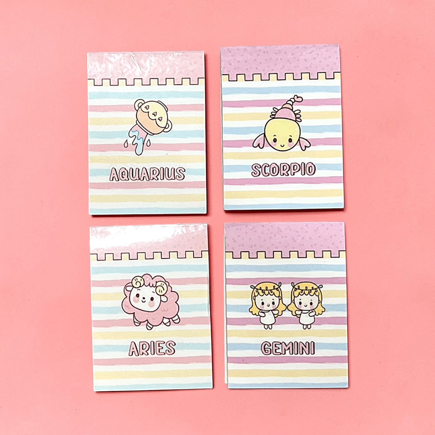 Four small bookmarks with zodiac signs on a pink background