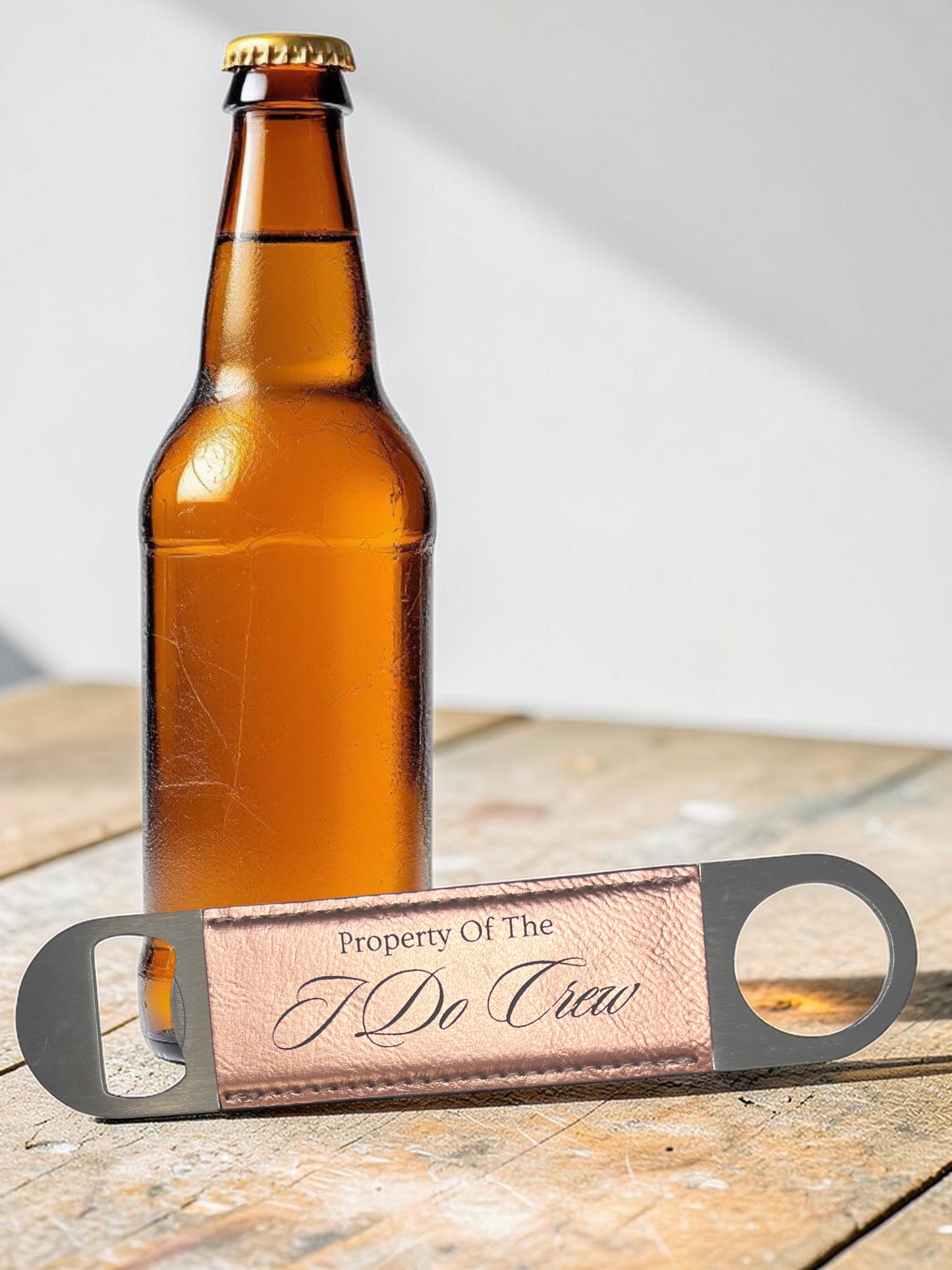 Brown beer bottle with a leather bottle opener on a wooden surface