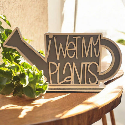 a watering can shaped shelf sitter home decor that reads I wet my plants