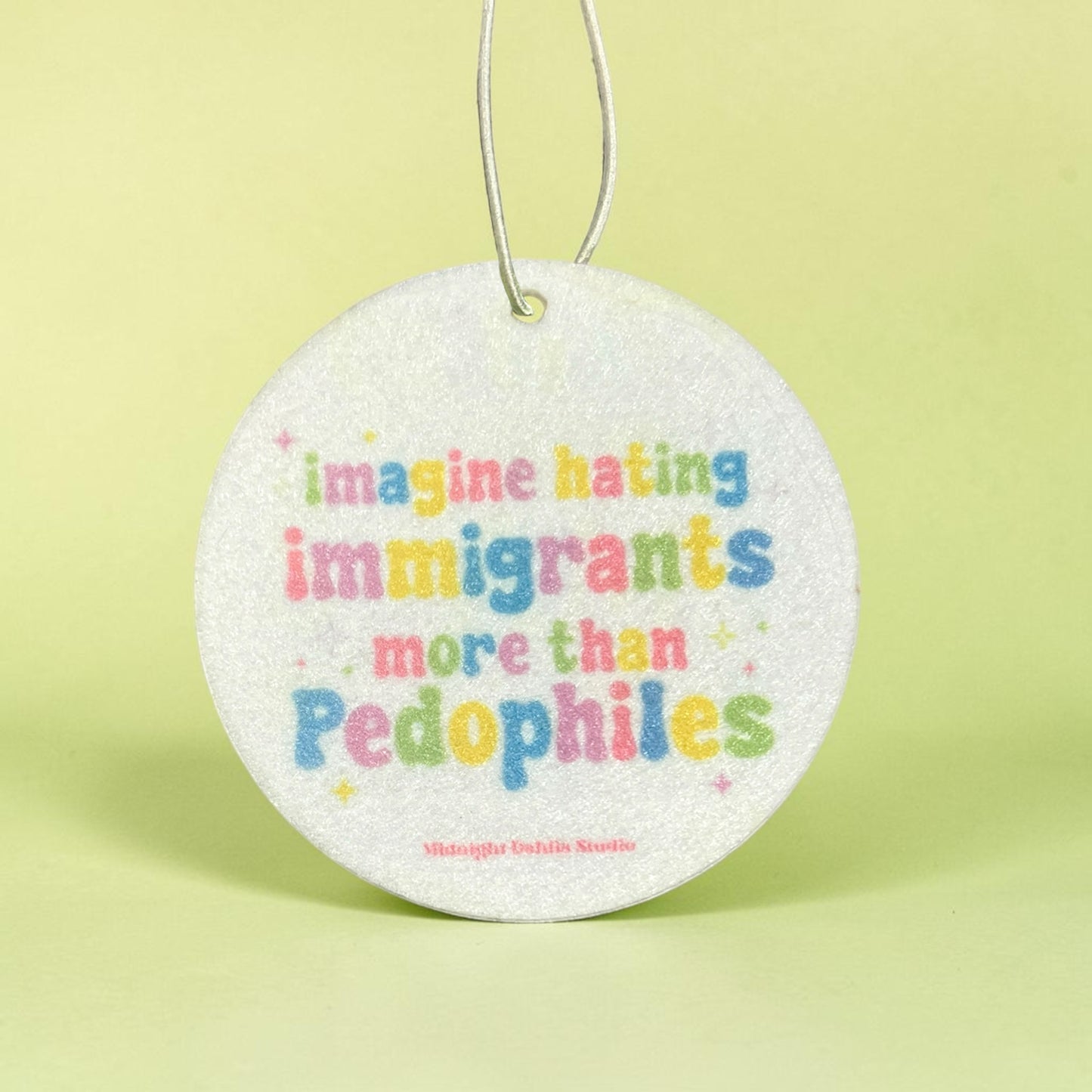 Round air freshener with colorful text on a light green background
