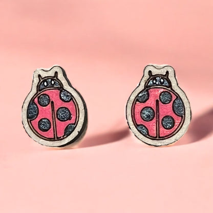 Pair of ladybug-shaped earrings on a pink background