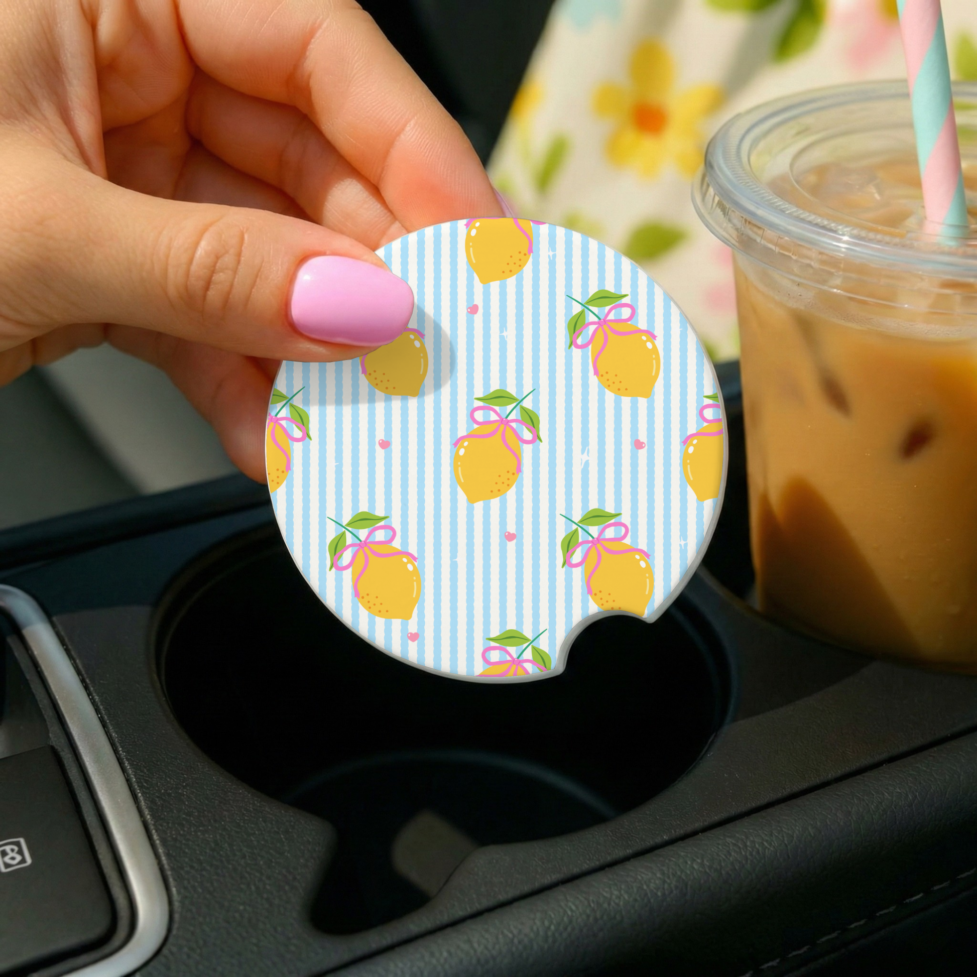 a hand holding a car coaster with a lemon theme