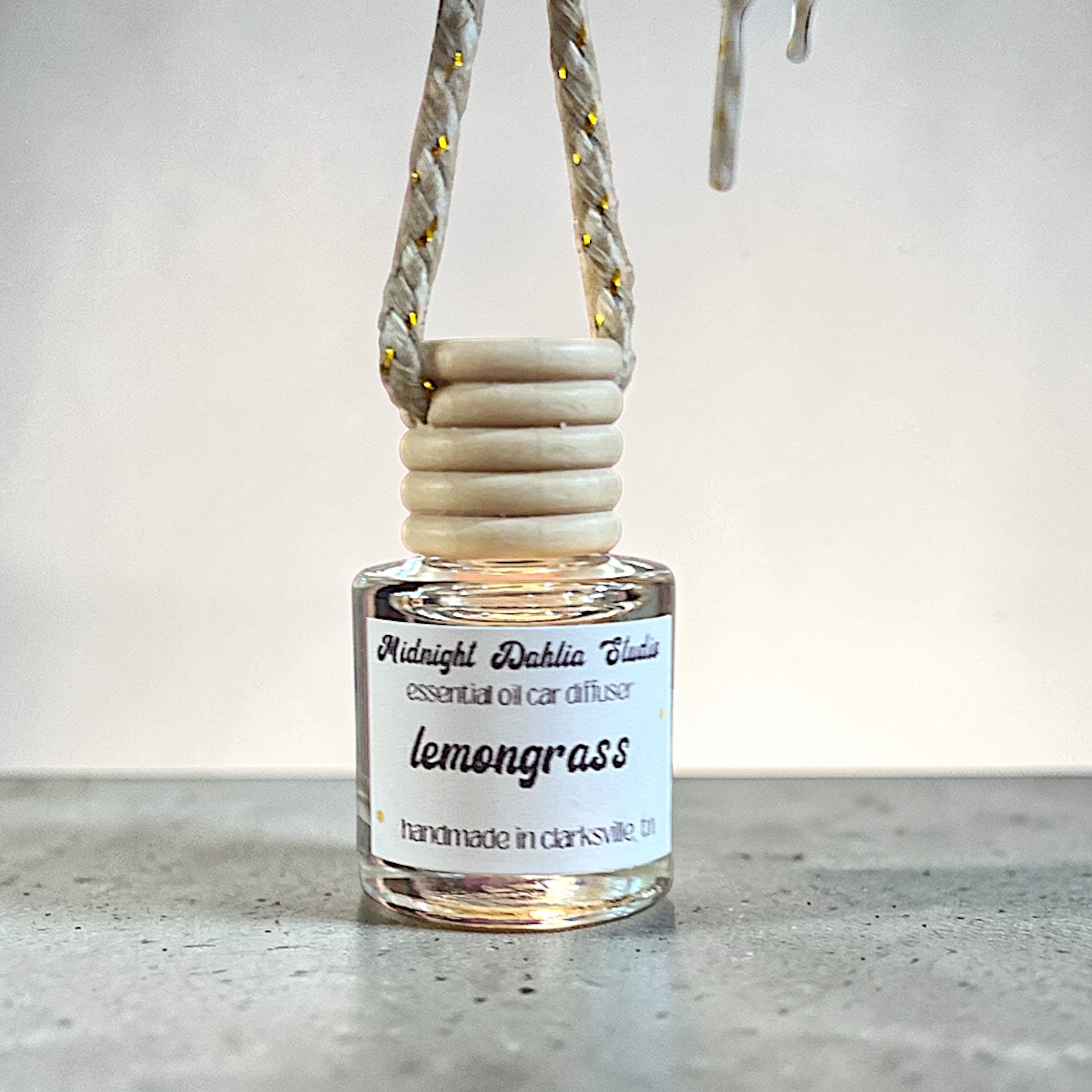 Glass diffuser bottle with lemongrass scent on a concrete surface