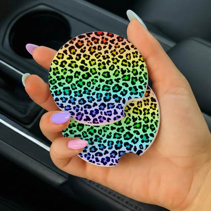 Hand holding a rainbow leopard print car coaster in a vehicle.