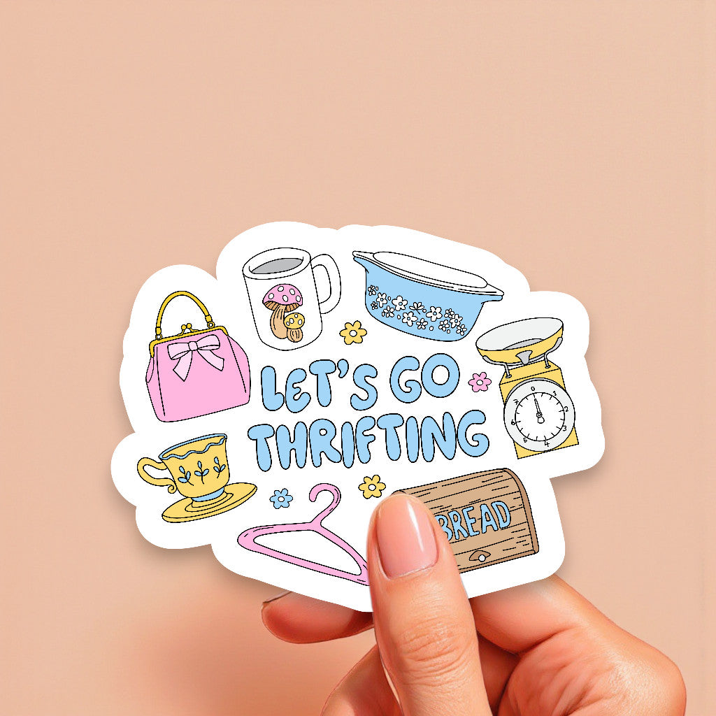 Sticker with thrift store items and 'Let's Go Thrifting' text held by a hand on a beige background