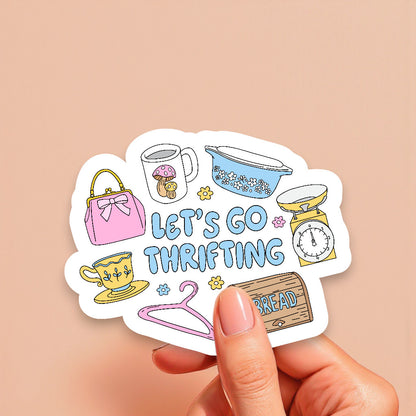 Sticker with thrift store items and 'Let's Go Thrifting' text held by a hand on a beige background