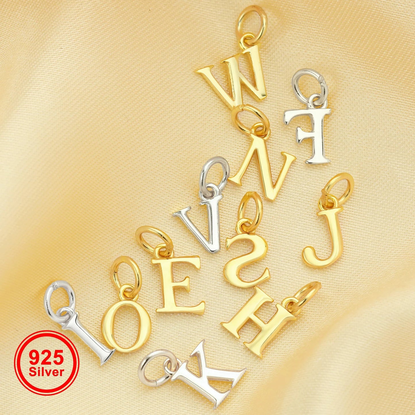 Gold and silver letter pendants on a gold background with '925 Silver' stamp.