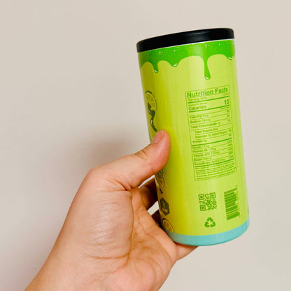 Hand holding a green cylindrical container with a label, against a plain background