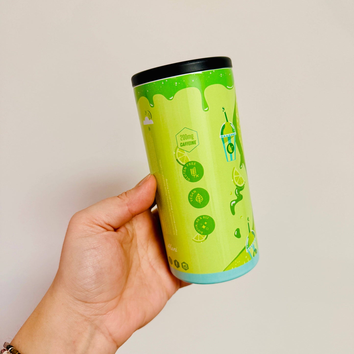 Hand holding a green cylindrical container with lime graphics on a plain background