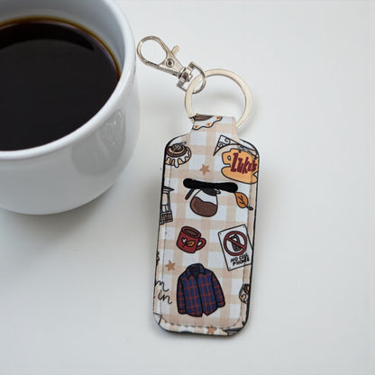 Keychain with coffee-themed design next to a cup of coffee on a white surface